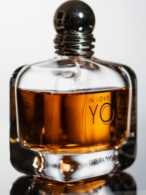 Close-up of luxury perfume bottle on glass surface with elegant curvature.